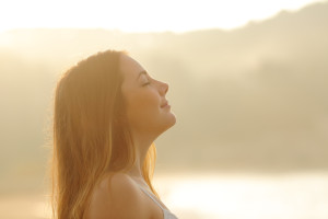 Woman breathing deep fresh air in the morning sunrise