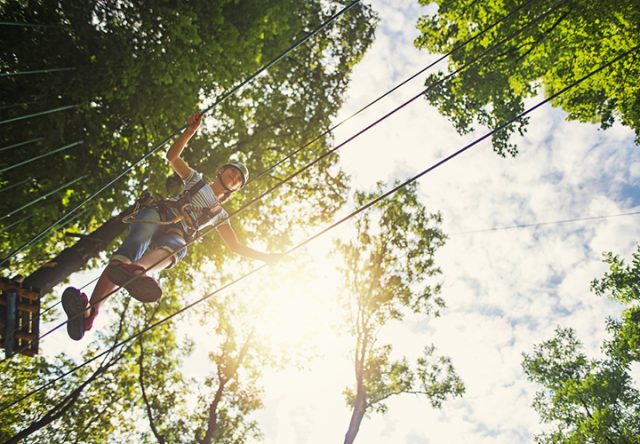 Teenage girl walking on a line in adventure park